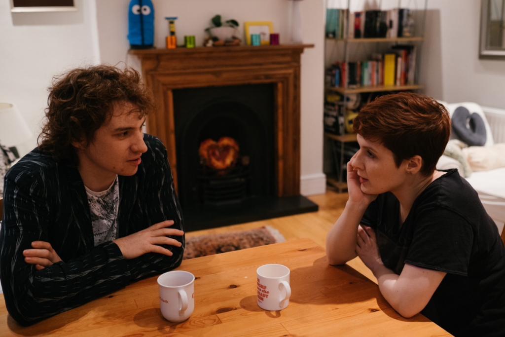 couple sat at kitchen table with cups of tea talking