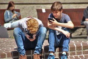 Two boys sitting on a step using their phones