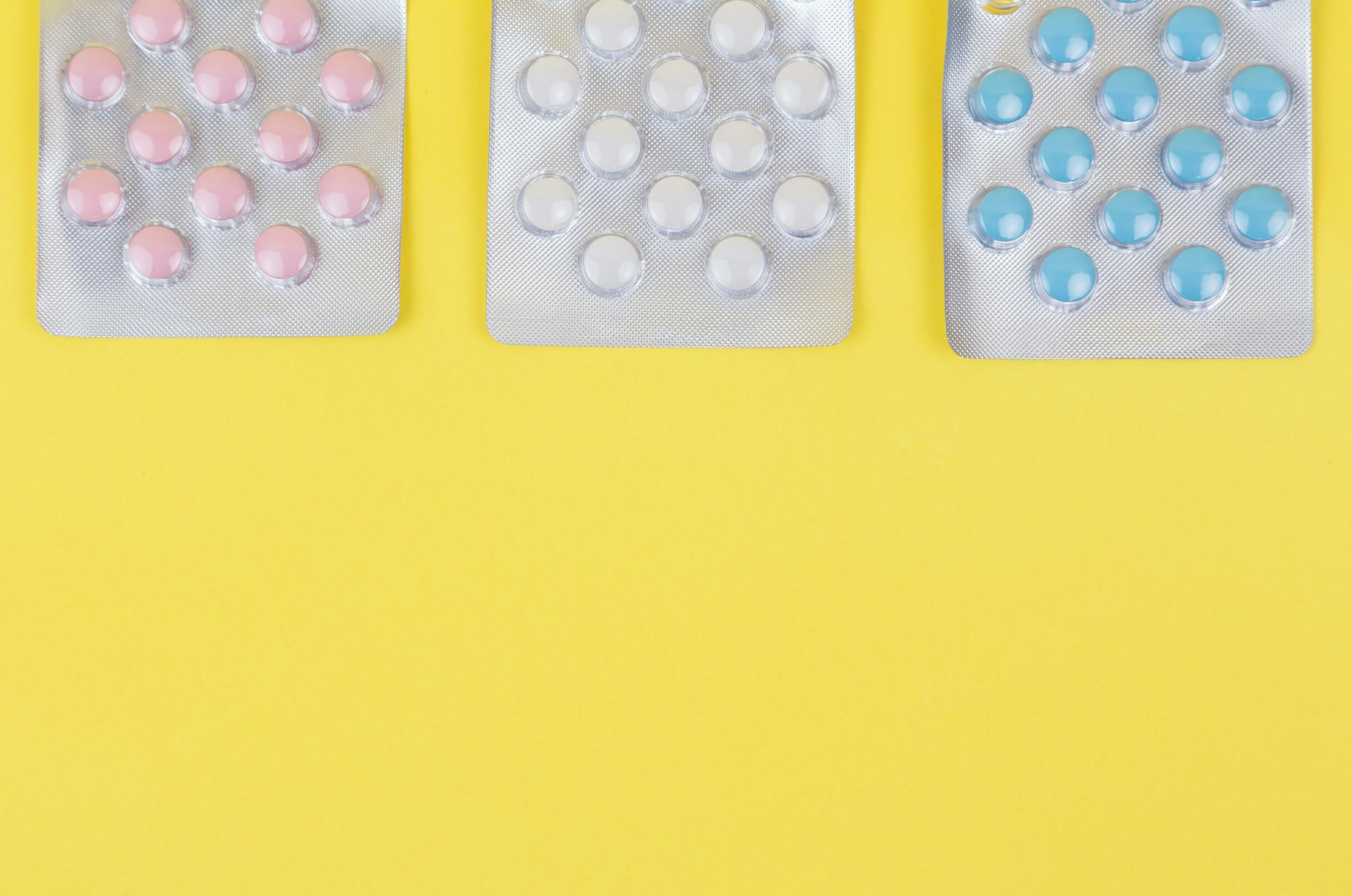 three packets of contraceptive pills against a yellow background