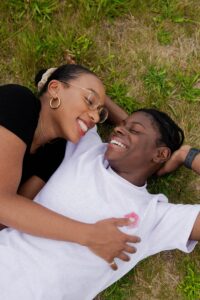 A couple lying on the grass smiling at each other