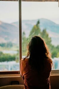 Woman looking out of a window with her back facing the camera