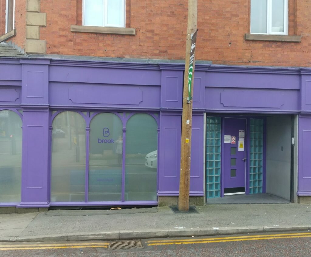 Purple door and entrance to Brook Blackburn. On ground floor of brick building