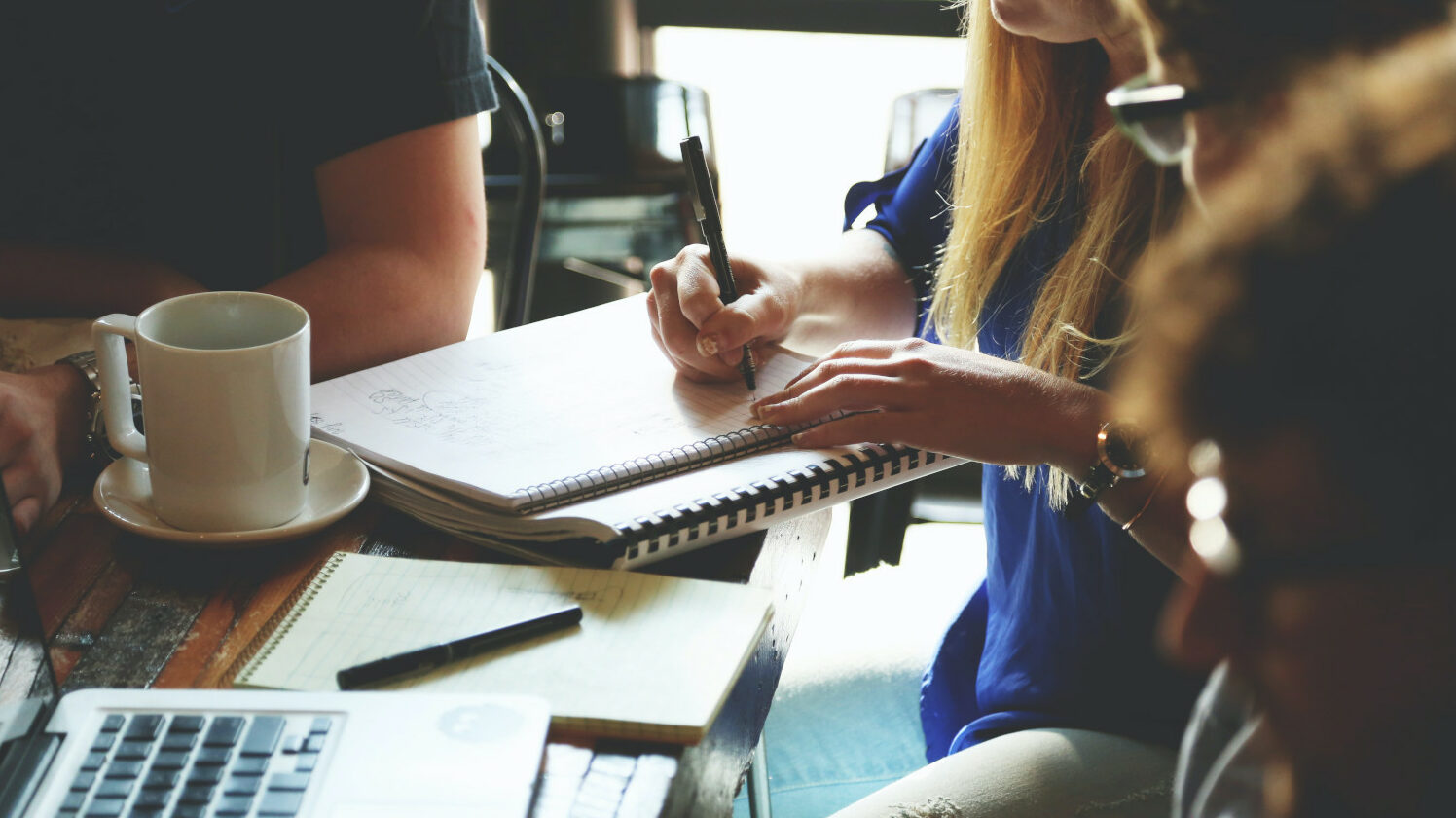 people sitting at a table writing in notebooks