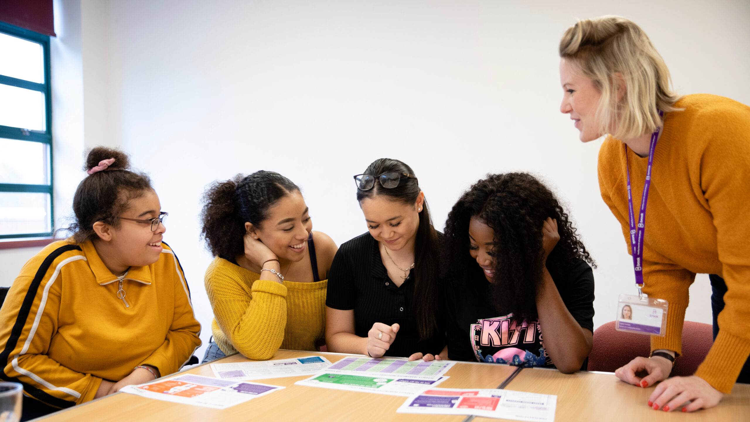 4 students at a table with a teacher standing next to them