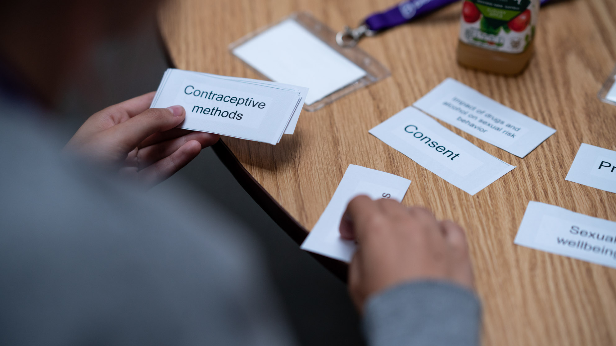 Person in classroom sorting out cards with sexual health terms on e.g. consent, contraception methods