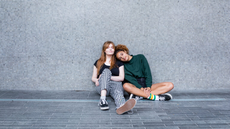 Two girls sat against a wall