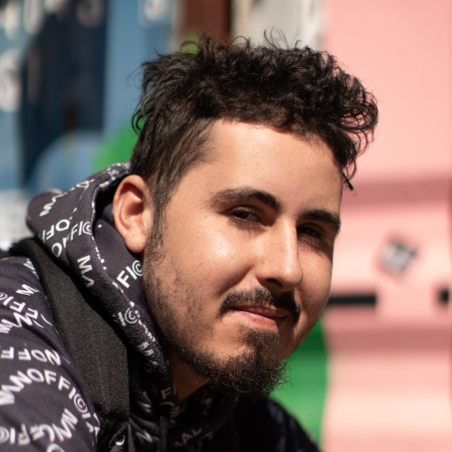 Young man with trimmed facial hair wearing a black jacket with white lettering