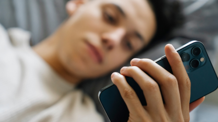 boy lying on his bed on his phone.