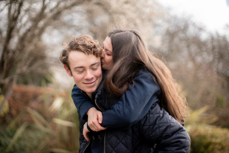 A young couple - one carrying the other on their back smiling
