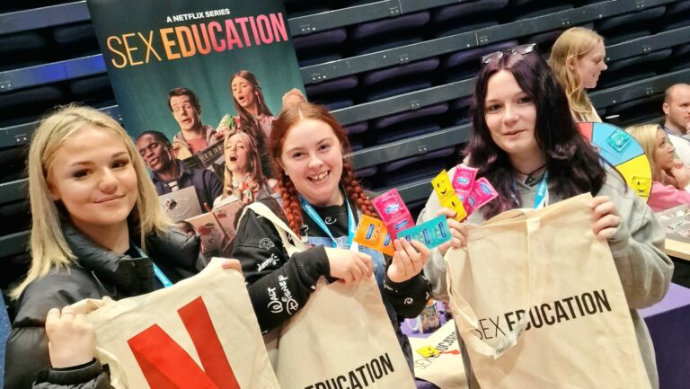 Students picking up Sex Education merchandise and condoms from a Brook stall