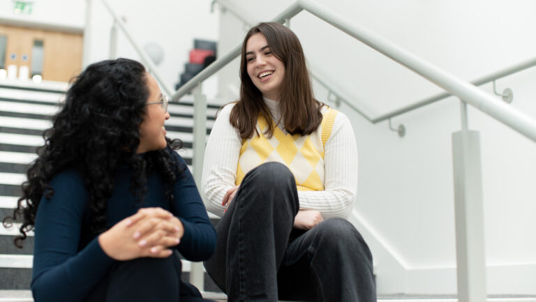 Two young women sitting on some stairs chatting