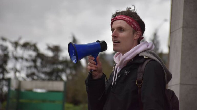 Jack talking into a megaphone wearing a bandana