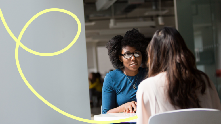 Two women sat facing each other talking in a professional environment