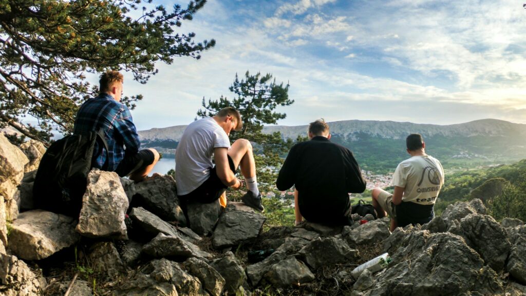 Four men sat at the top of a mountain looking at the view