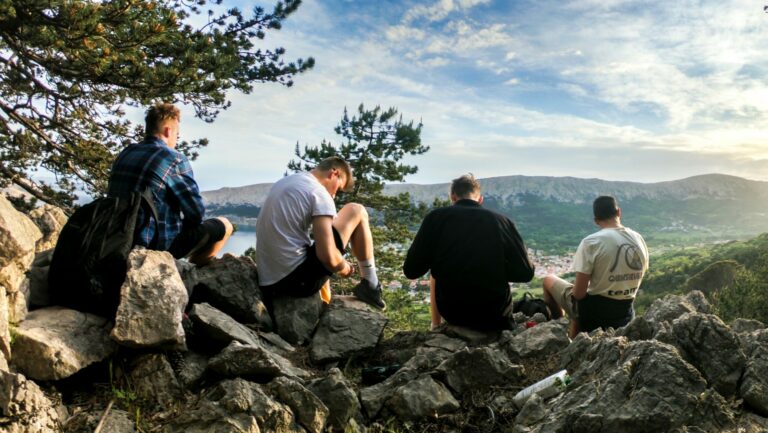 Four men sat at the top of a mountain looking at the view