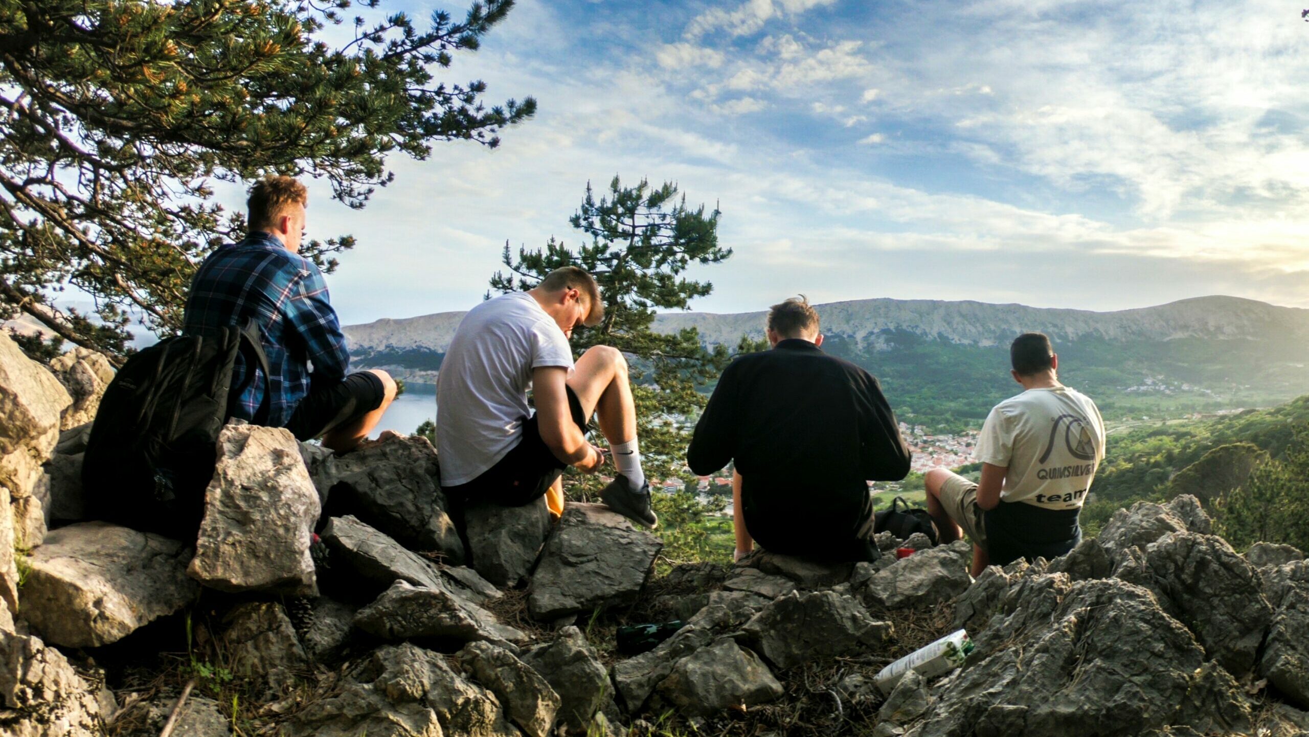 Four men sat at the top of a mountain looking at the view