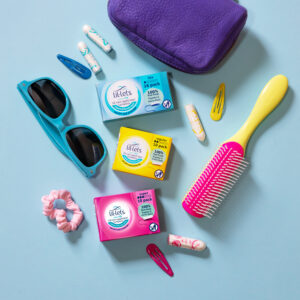 Assortment of things you might keep in your bag including sunglasses, scrunchie, hairbrush, lil-lets tampons and hair grip
