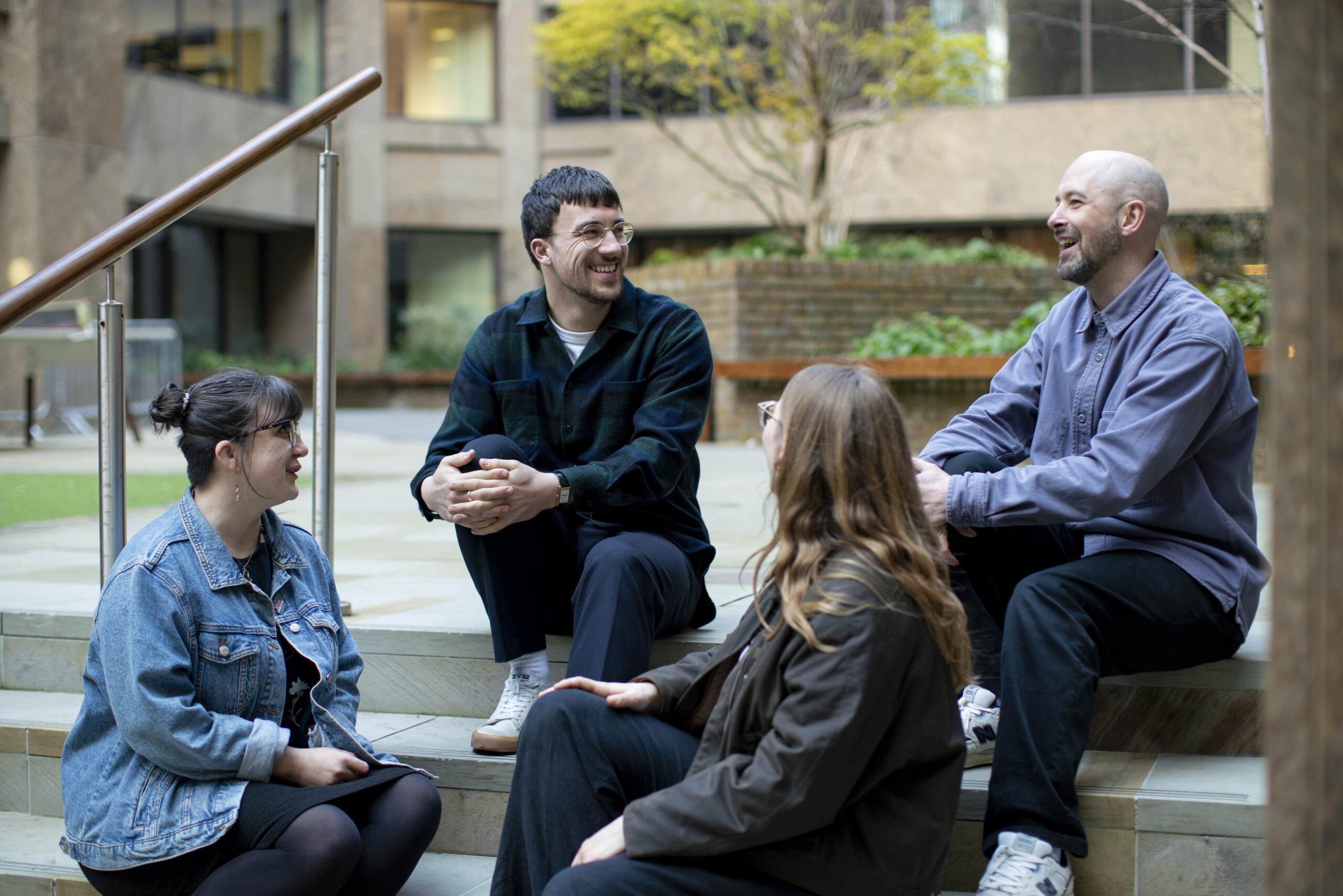 Four Brook staff members sat on stairs chatting