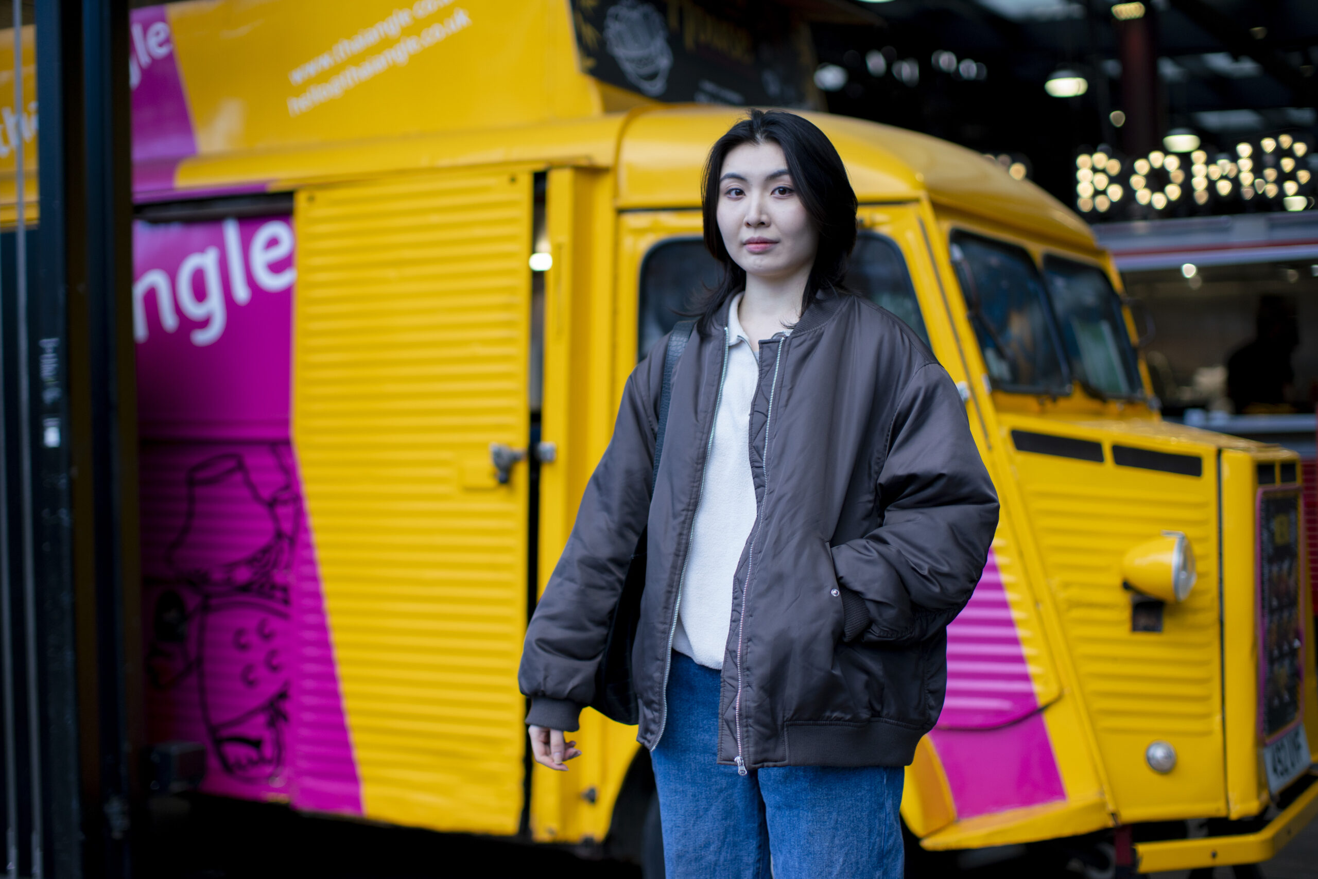 A woman stands in front of a bright yellow food truck