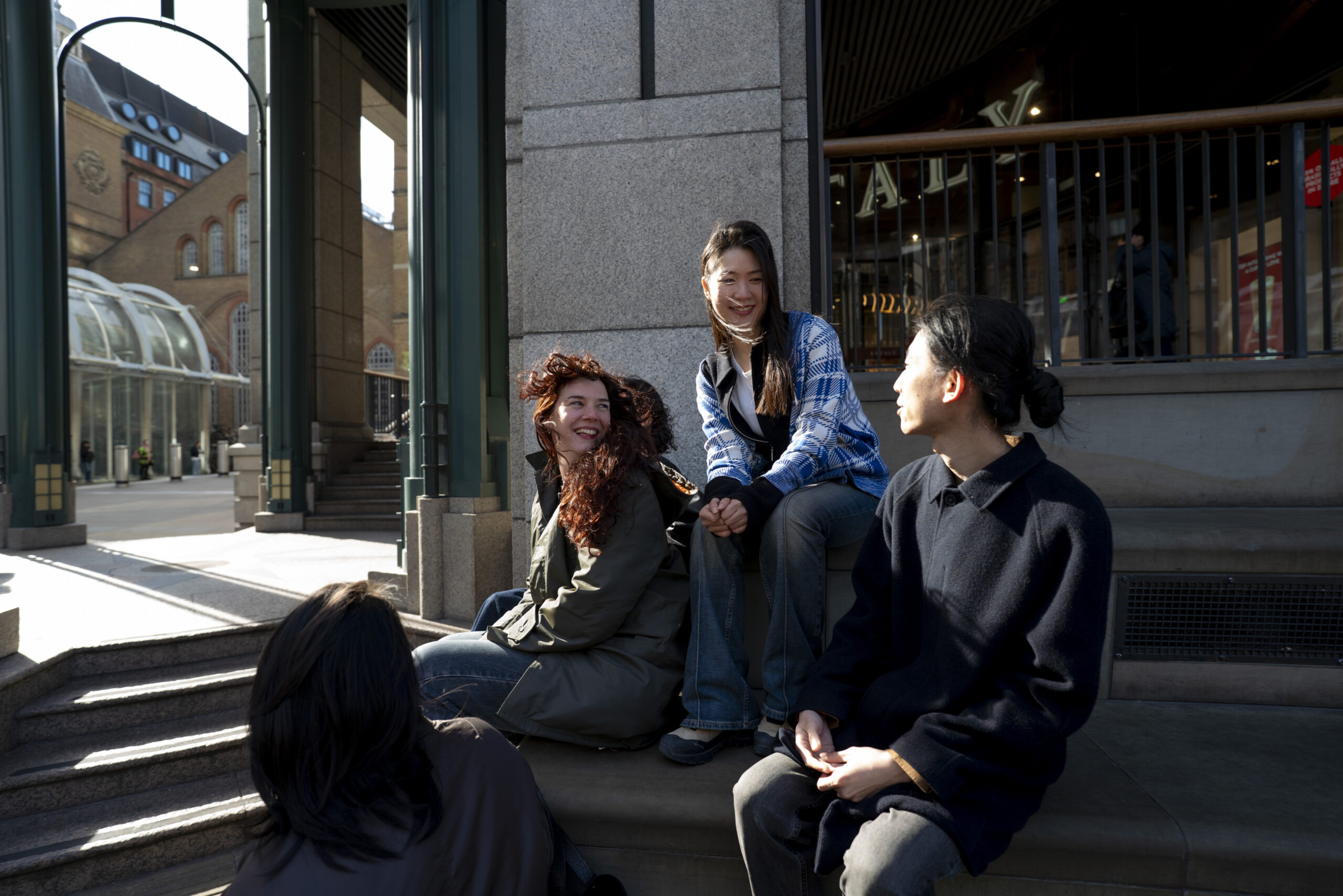 Three people sit on concrete steps smiling at each other