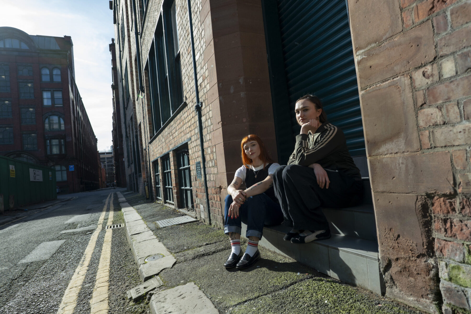 Two young adults sit on a kerb