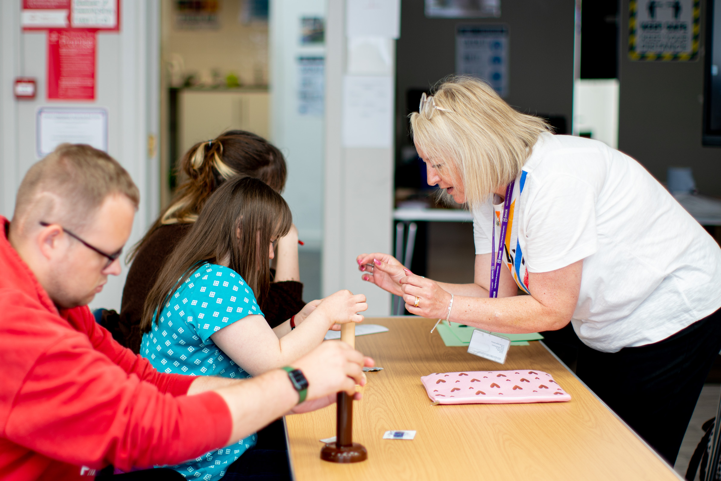 A tutor teaches three students how to use a condom