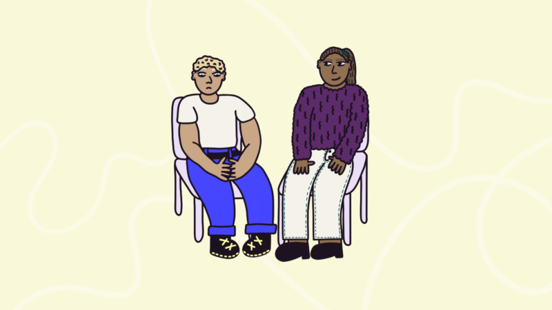 Two people sat on chairs, with one person upset