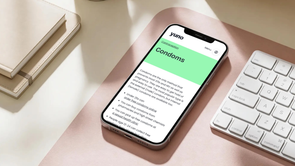 An iPhone sitting on a desk, displaying the Yuno condoms page