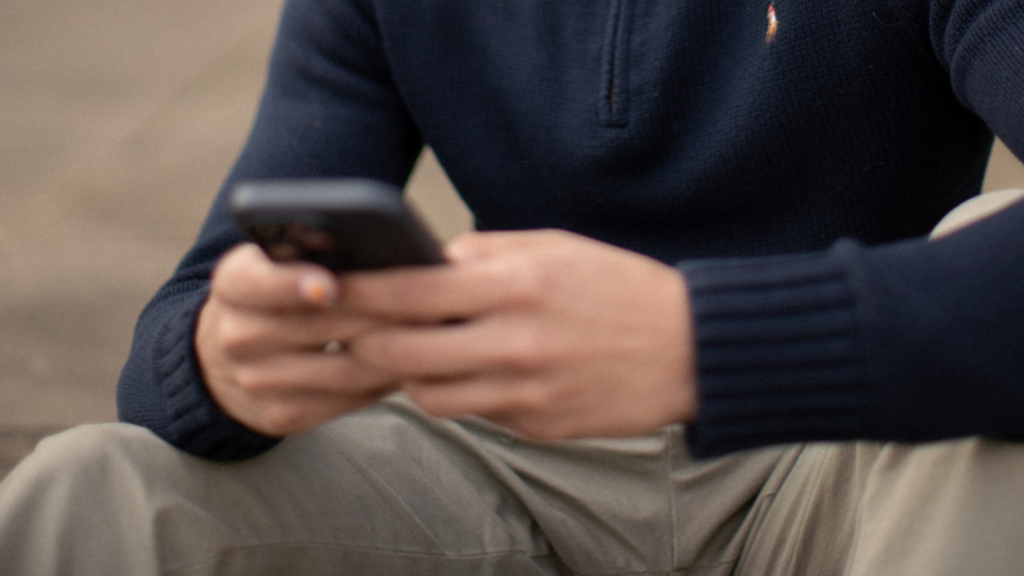 A blurred image of someone holding a phone while sitting down