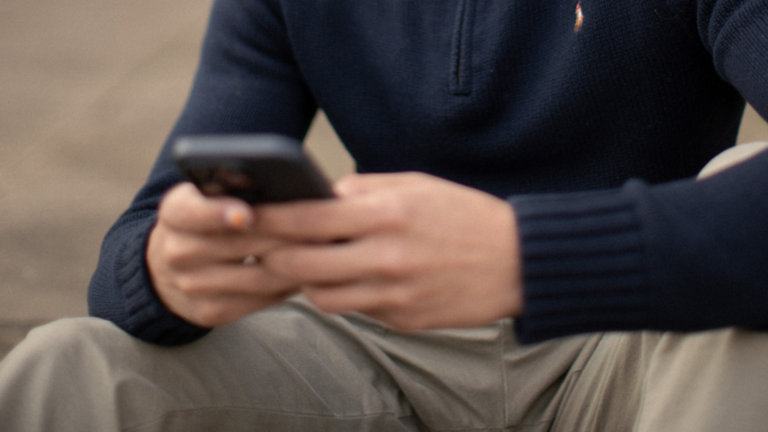 A blurred image of someone holding a phone while sitting down