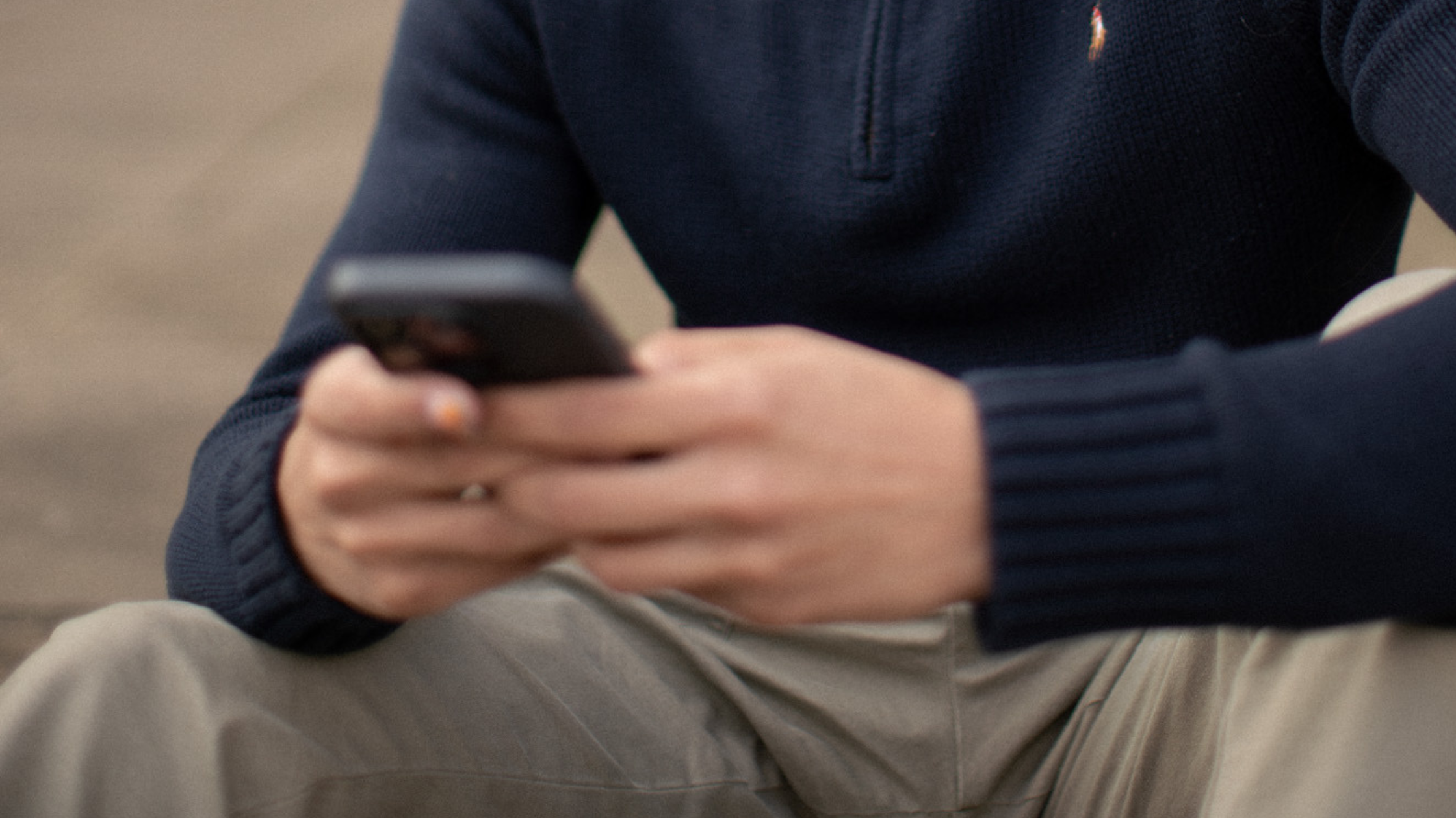 A blurred image of someone holding a phone while sitting down
