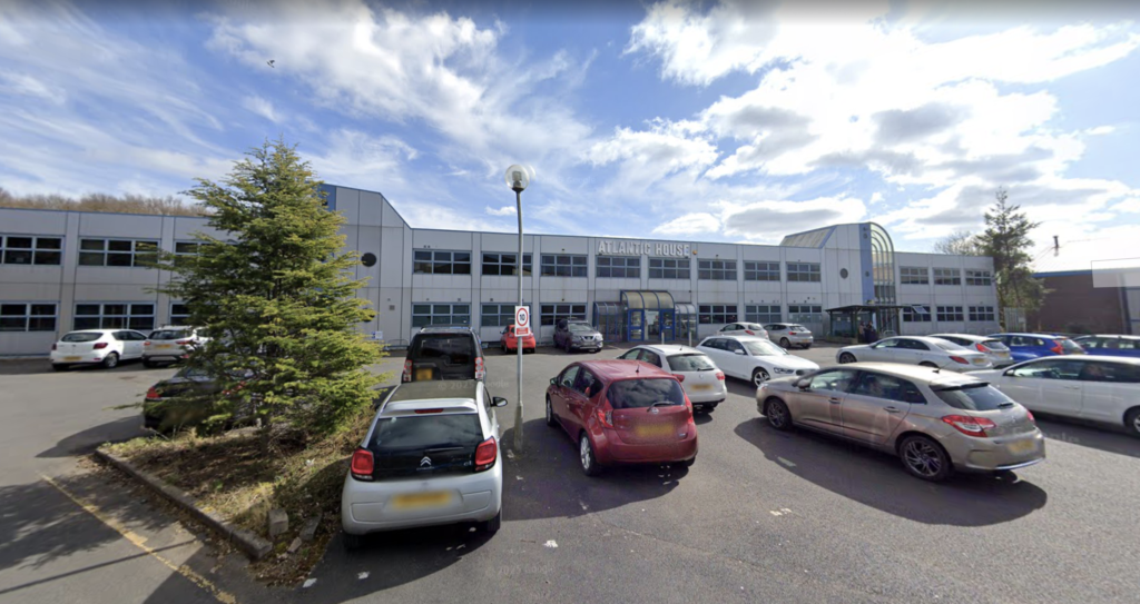 Outside Atlantic House - A large carpark out front with a grey two-storey building with a flat roof